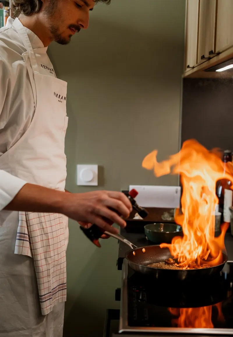 Chef Constant flambe une poêle de champignons dans une cuisine