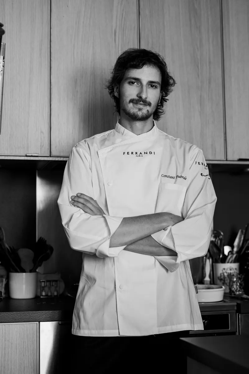 Portrait en noir et blanc de Constant, bras croisés, en veste de cuisine Ferrandi