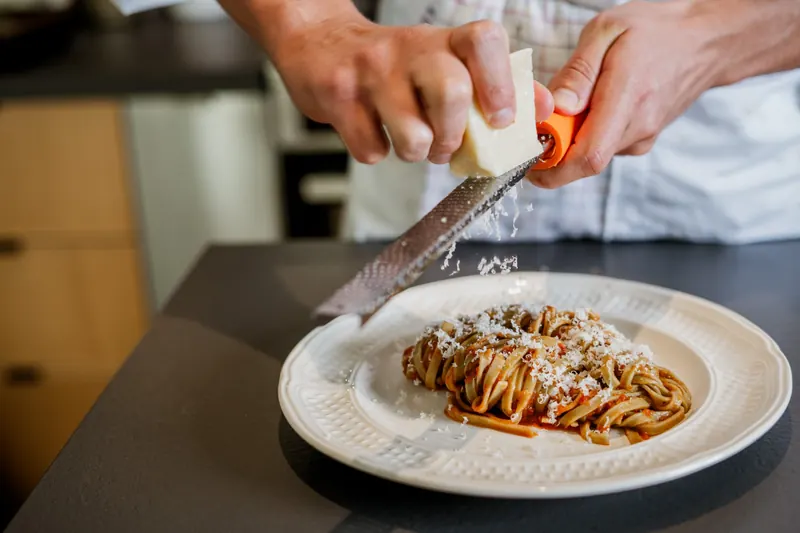 Parmesan râpé sur une assiette de tagliatelles fraîches à la sauce tomate